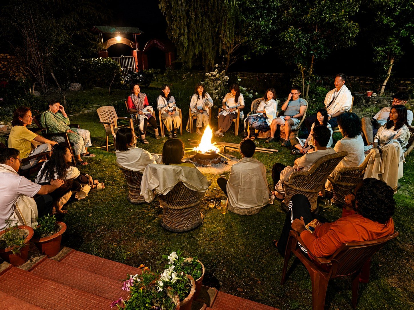 A mixed group sitting together around an evening bonfire in conversation at Our Himalayan Home