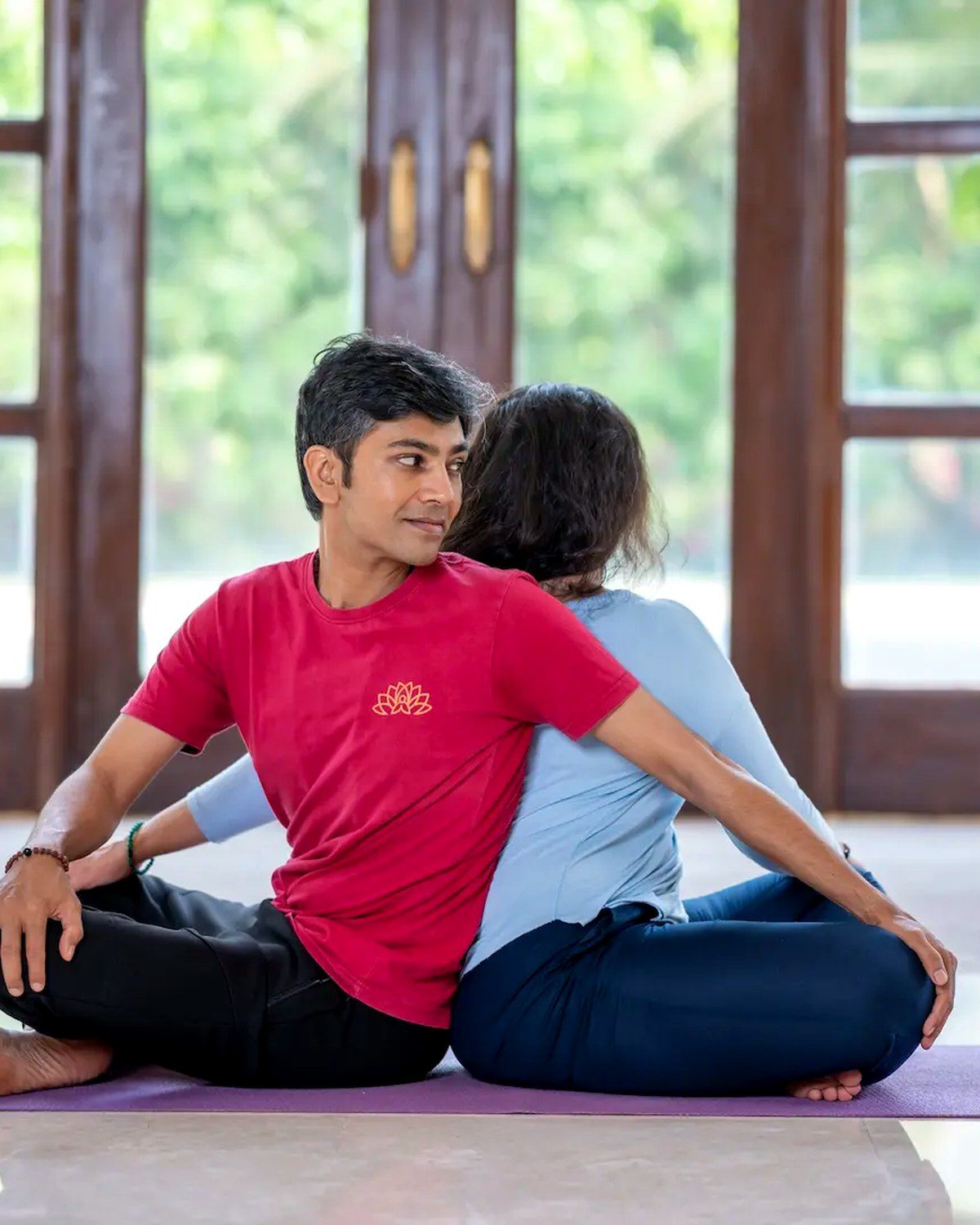 A couple sitting back to back, connected, after a shared yoga practice