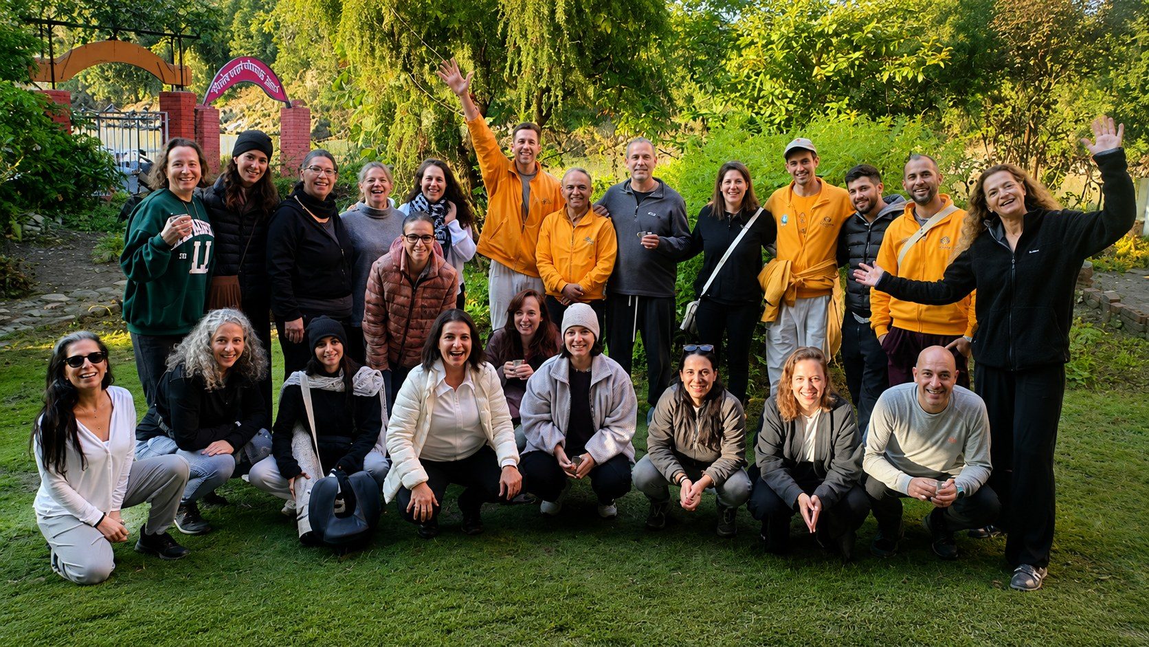 A mixed group of participants gathered together and smiling in the garden at Our Himalayan Home