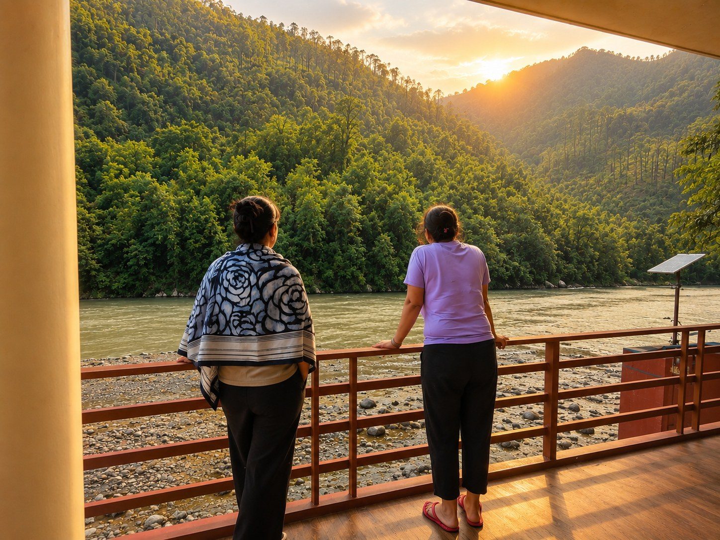 Two students looking out over the Bhagirathi River from a covered veranda at sunset